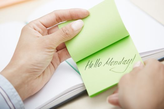 Hands holding sticky note with Hello Monday text