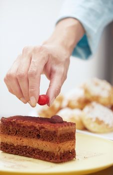 Woman putting berry to the chocolate cake