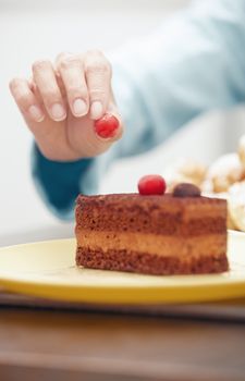 Woman putting berry to the chocolate cake