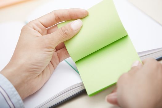 Hands holding green sticky note with empty space