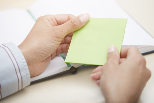 Hands holding green sticky note with empty space