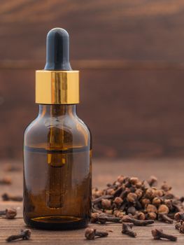 Spice clove essential oil in dark glass bottle anddry cloves on dark wooden background with copy space