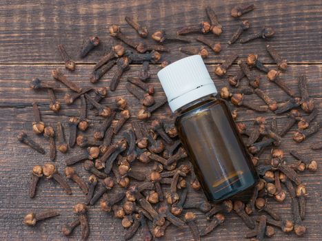 Spice clove essential oil in dark glass bottle anddry cloves on dark wooden background. Top view or flat lay