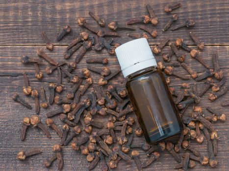 Spice clove essential oil in dark glass bottle anddry cloves on dark wooden background. Top view or flat lay