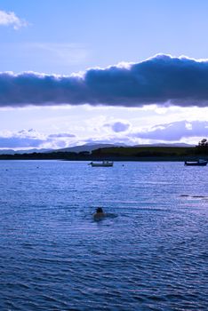 man swimming in a quiet bay near kenmare on the wild atlantic way ireland with a cold blue sunset