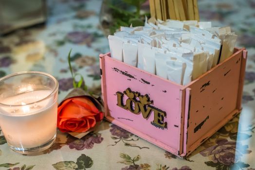 wooden pink box with white stickers. Candle in the glass and rose flower