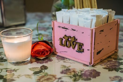 wooden pink box with white stickers. Candle in the glass and rose flower