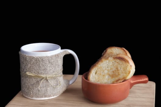 Mug with tea and toast on the Board and black background. Selective focus.