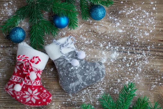 Christmas and New Year winter holiday snowbound composition of stockings on wooden space background with green fir tree branches and balls ornament