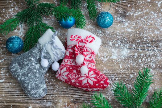 Christmas and New Year winter holiday snowbound composition of stockings on wooden space background with green fir tree branches and balls ornament