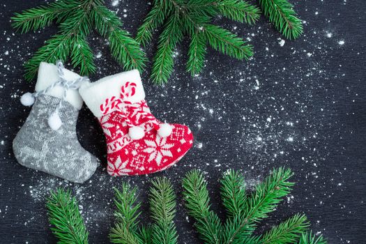 Christmas and New Year winter holiday snowbound composition of grey and red stockings on black space background with green fir tree branches