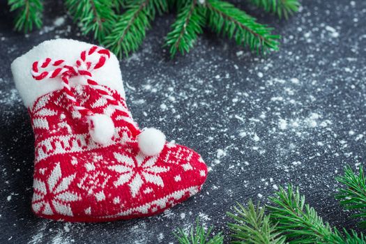Christmas and New Year winter holiday snowbound composition of red stocking on black space background with green fir tree branches