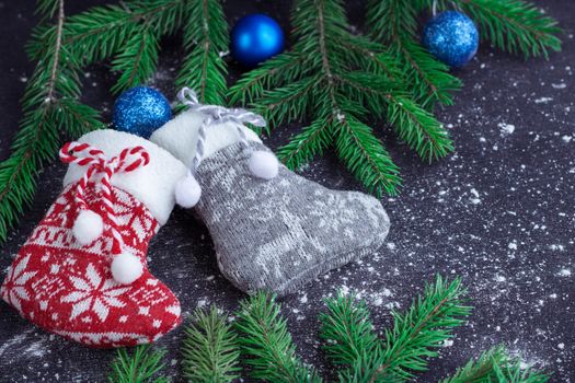 Christmas and New Year winter holiday snowbound composition of red and grey stockings on black space background with green fir tree branches and blue balls ornament