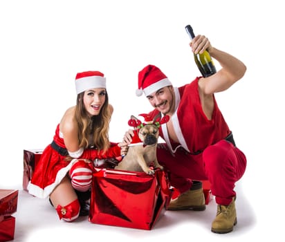 Handsome young man and pretty young woman in Santa Claus hat and costume, with pug dog, standing holding colorful festive Christmas gifts to celebrate the season, on white background