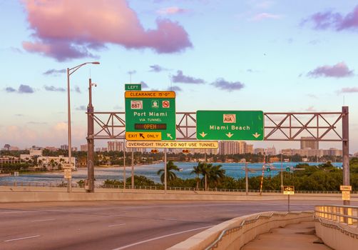 Road signs for Miami Beach, Florida, USA, at MacArthur Causeway at sunset.