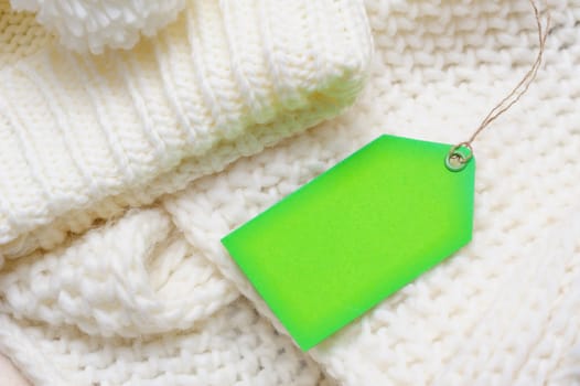 white texture knitted scarf and hat with a green tag.