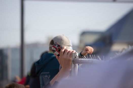 crowd of people behind the fence, hand holding phone