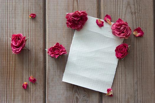 note and dry pink roses on wooden table