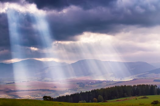 Sunlight beams over clouds in Tatra mountains. Rays in cloudy sky