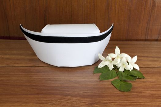 Hat nurse white and Millingtonia hortensis flowers on wood table. symbol of nursing thailand and Thai traditional medicine.