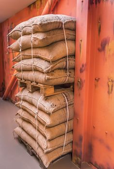 Industrial image of two pallets with goods in burlap sacks,  piled upon each other and stacked in a storage, prepared for shipping.