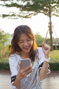 young asian  woman watching to mobile phone screen with surprising and happiness face