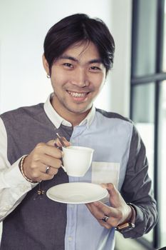 asian younger man toothy smiling face with hot coffee cup in hand