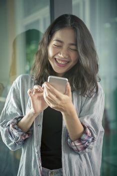 asian younger woman laughing with happiness emotion looking and reading chat message  on smart phone