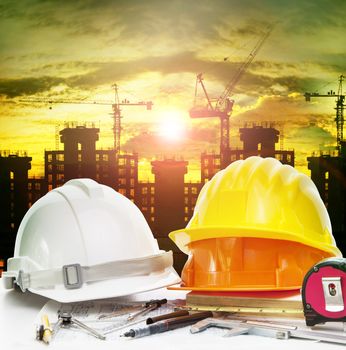 safety helmet on engineer working table and construction site background