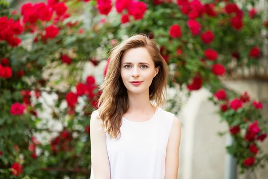 Close up portrait of lovely urban girl outdoors. Portrait of a happy smiling woman among the roses.