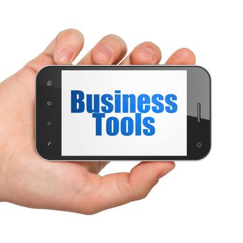 Business concept: Hand Holding Smartphone with  blue text Business Tools on display,  Tag Cloud background, 3D rendering