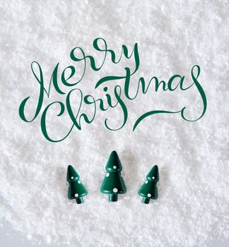 Three Miniature Christmas Trees on snow with text Merry Christmas. Lettering calligraphy.