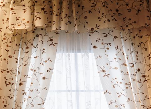 Beautiful curtains with flowers paint in a room.