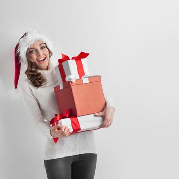Happy woman in Santa hat with stack of Christmas gifts
