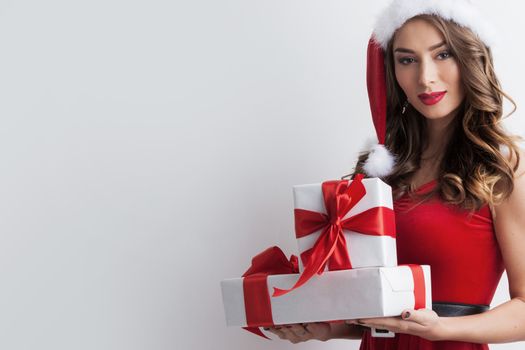 Beautiful hispanic woman in red santa claus costume holding Christmas gifts