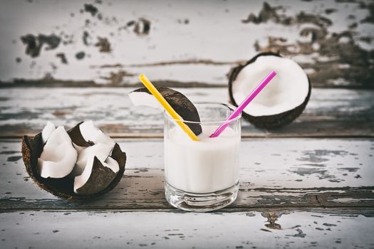 Coconut and coconut milk in a glass over a wooden background