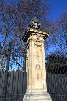 Column in stone between two gratings with a basin decorated with laurels