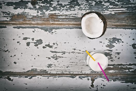 Coconut milk and half coconut seen from above over an old table