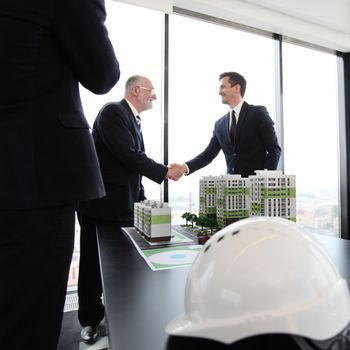 Meeting of business people of construction industry in office with house model on table