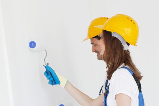 Team of young workers in hardhats painting the wall