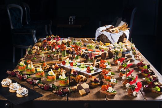 Snacks set. Brushettas, canapes, salads, desserts, tartlets, oysters on wooden table 