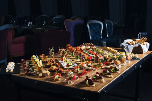 Snacks set. Brushettas, canapes, salads, desserts, tartlets, oysters on wooden table 