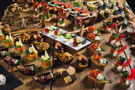 Snacks set. Brushettas, canapes, salads, desserts, tartlets, oysters on wooden table 