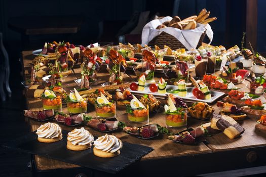 Snacks set. Brushettas, canapes, salads, desserts, tartlets, oysters on wooden table 