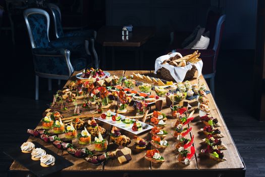 Snacks set. Brushettas, canapes, salads, desserts, tartlets, oysters on wooden table 