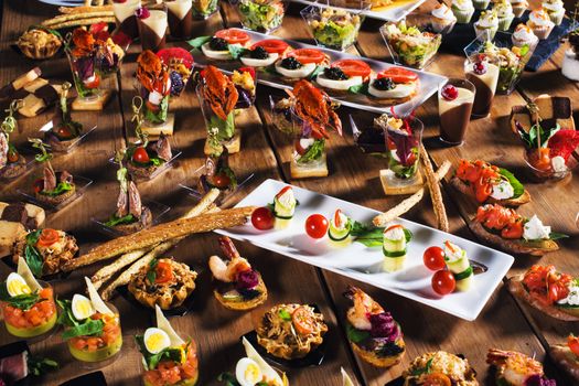 Snacks set. Brushettas, canapes, salads, desserts, tartlets, oysters on wooden table 