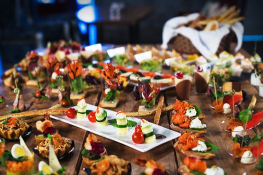 Snacks set. Brushettas, canapes, salads, desserts, tartlets, oysters on wooden table, selective focus