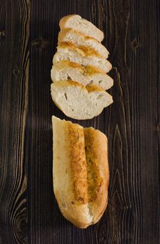 Top view of a sliced of baguette with cheese, dark wooden background