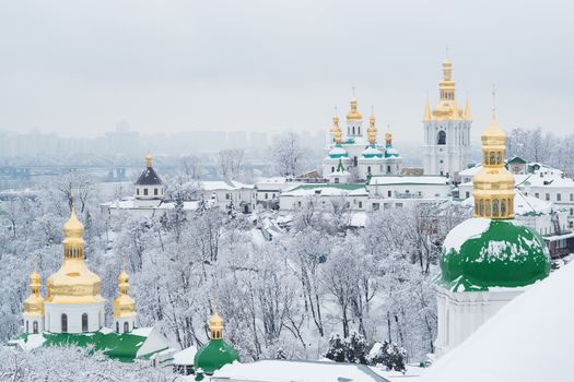 A view on Kiev Monastery of the Caves in winter with cloudy sky and snow and the city in the background