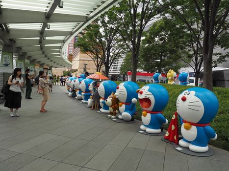 Tokyo, Japan - July 18, 2016: People are visiting the Doraemon model exhibition held at Roppongi neighborhood, Tokyo. Some people are taking their family member the photography with the curved line of the Doraemon models.